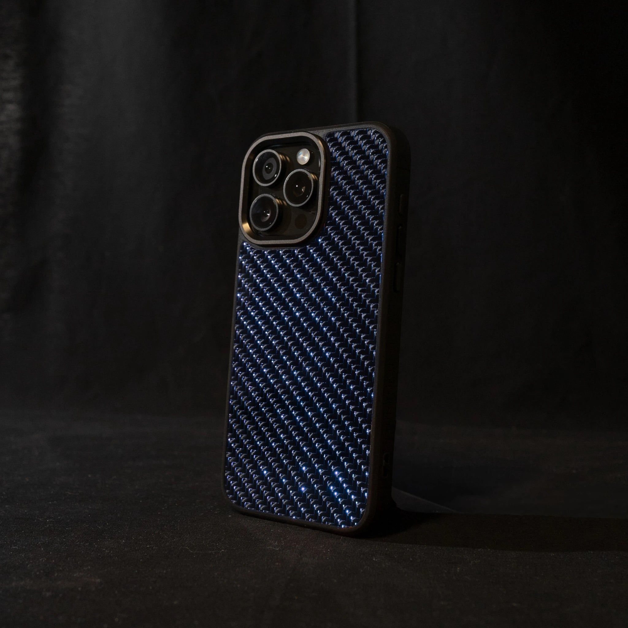 Blue carbon fiber phone case on a black background angled sideways