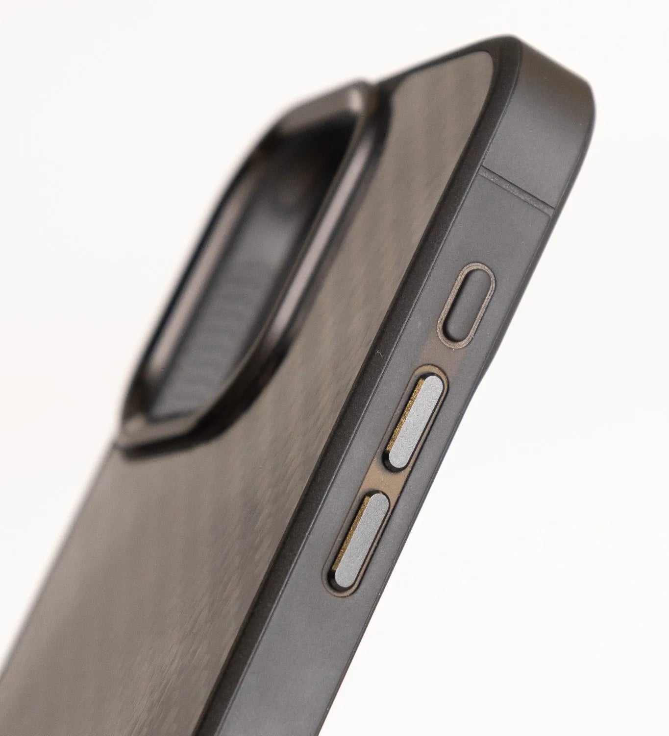 Close-up of carbon fiber phone case showing side aluminum buttons and FibreCases branding