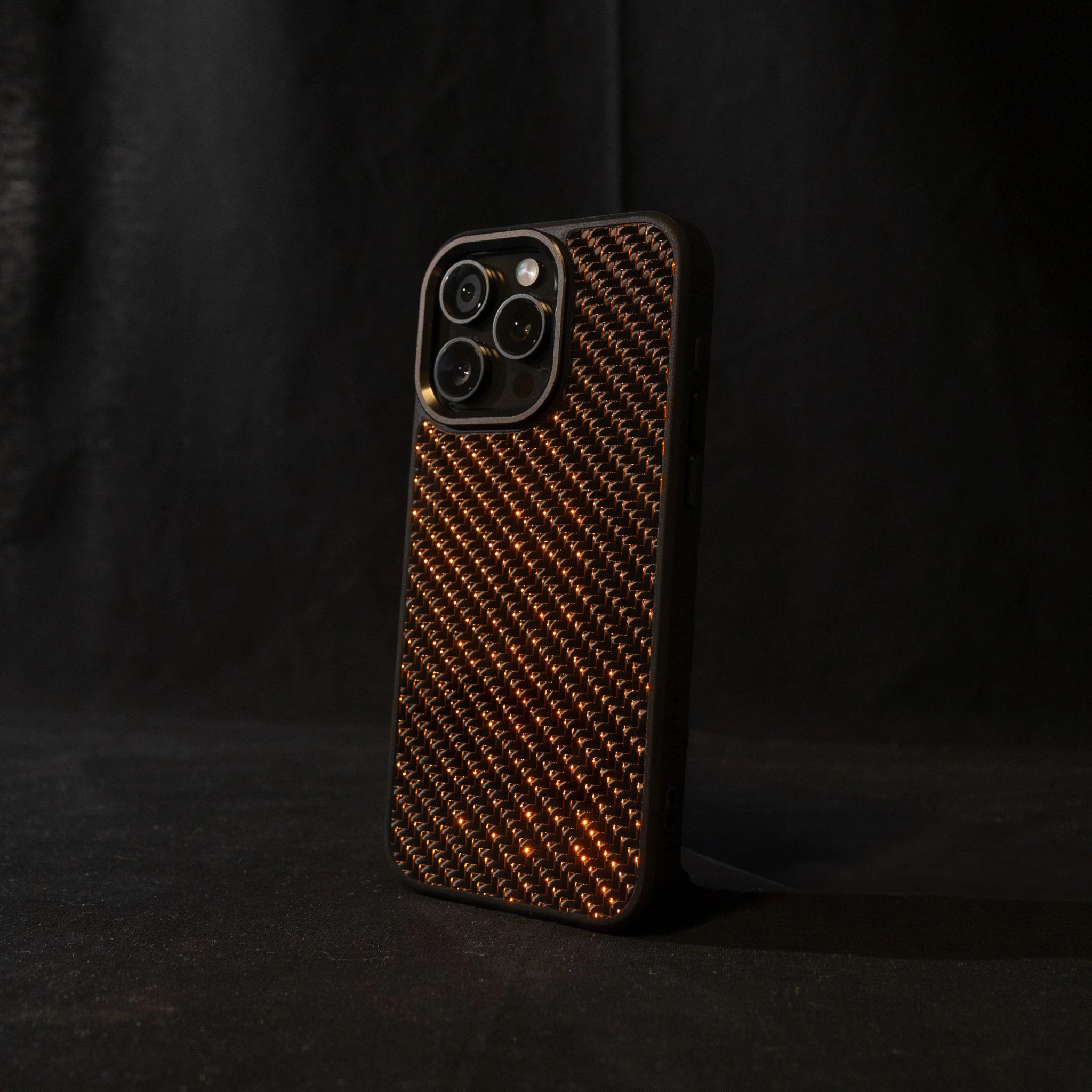 Orange carbon fiber phone case on a black background angled sideways

