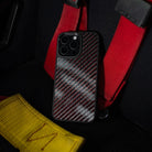 Phone case with carbon fiber on a red four point seatbelt


